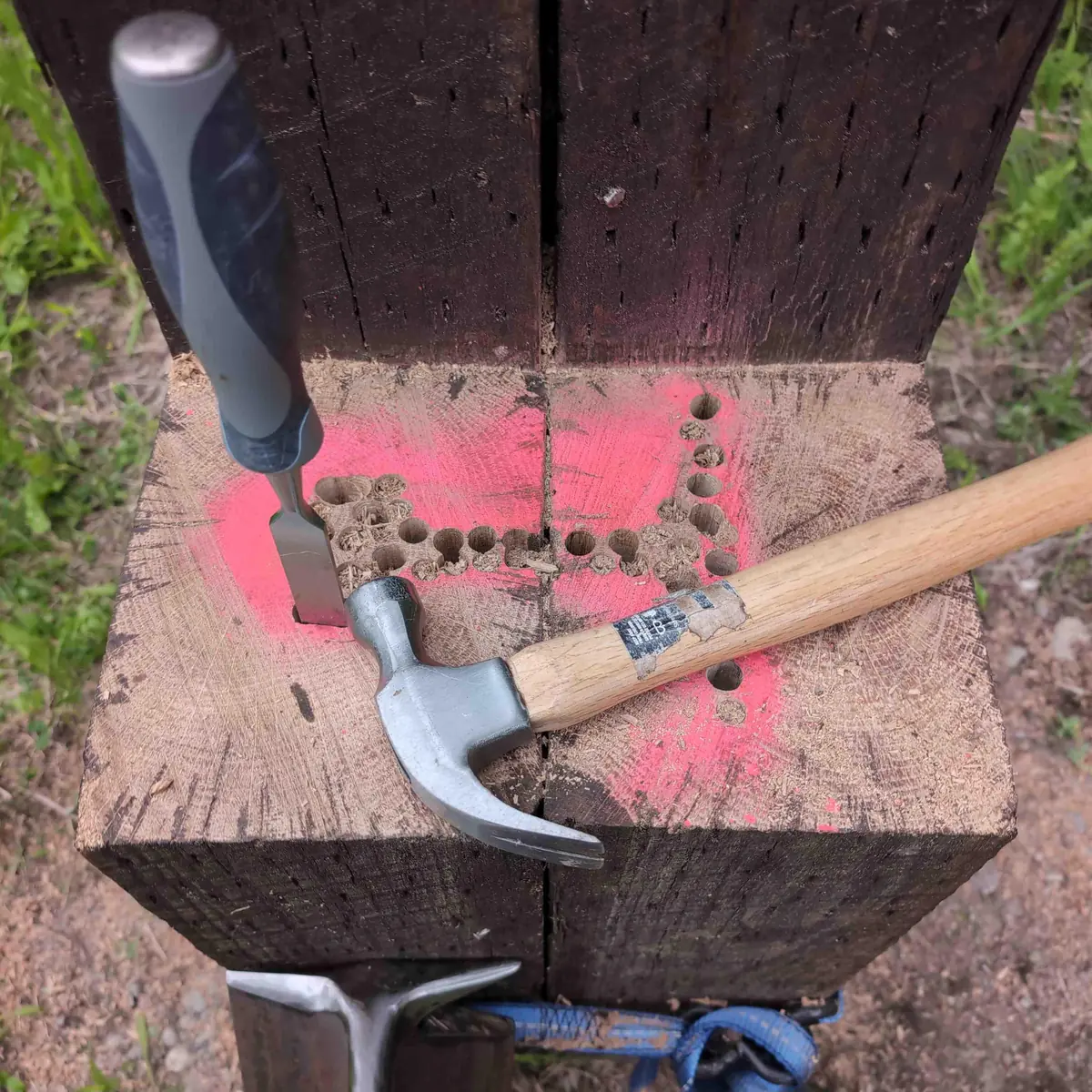 A chisel being used to clear out the remainder of wood after being drilled.